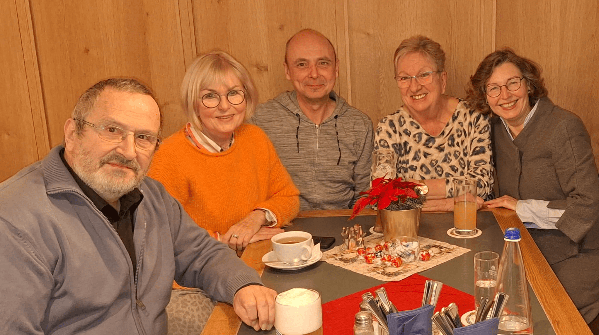 Treffen einer Gruppe von lächelnden Rentnern, an einem Tisch sitzend