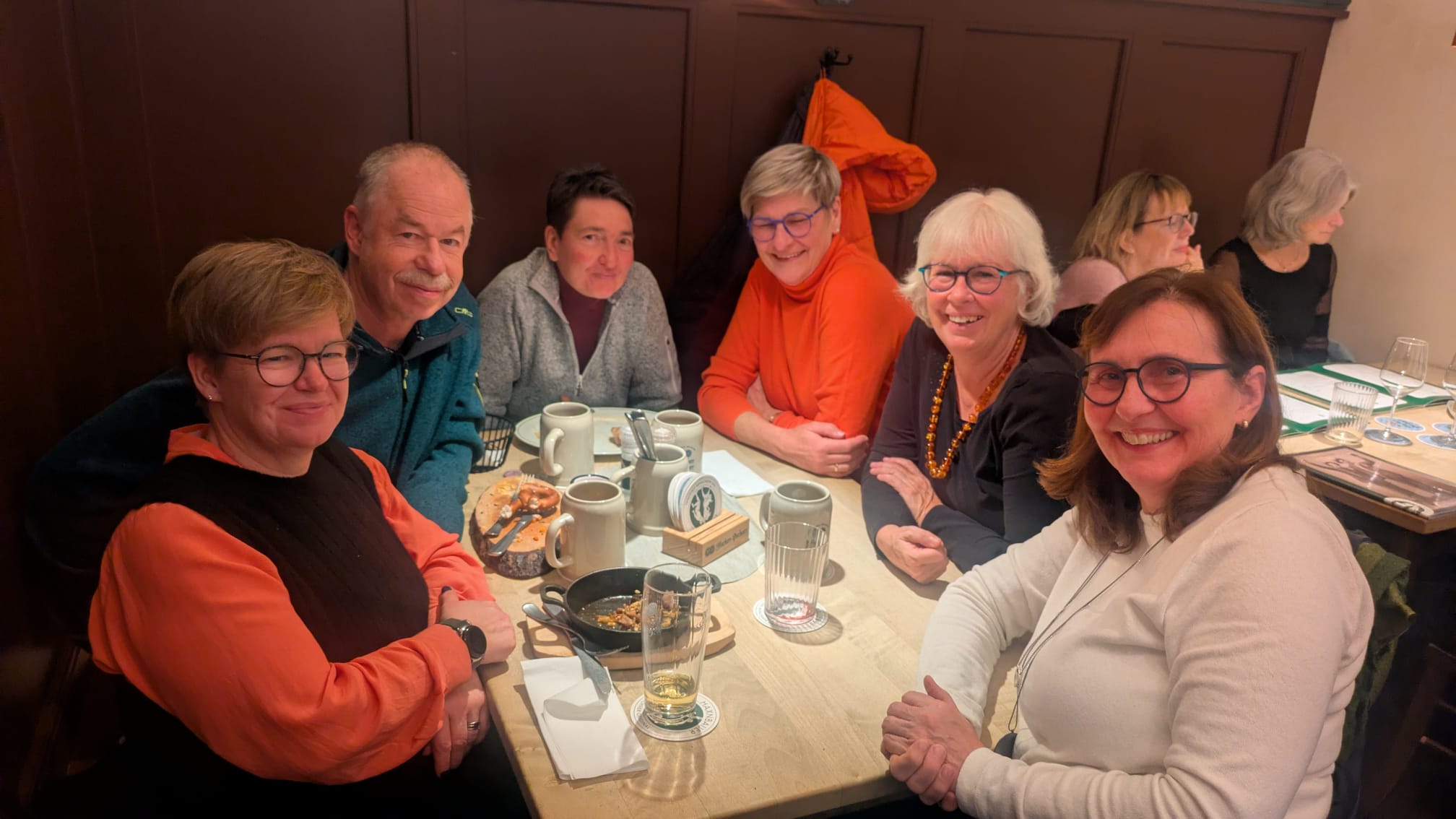 Eine Gruppe Frauen mit einem Mann sitzen um einen Tisch in einem Lokal herum und schauen freundlich in die Kamera